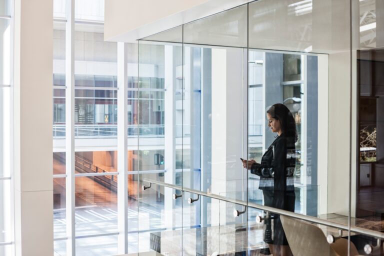 Businesswoman standing in a conference room window in a large business center.